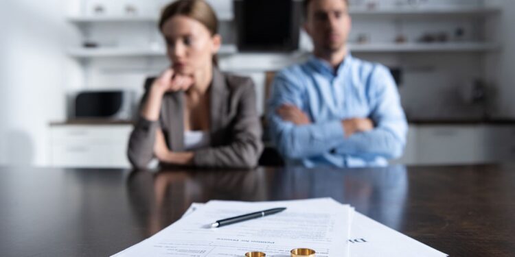 selective focus of couple sitting at table with divorce documents