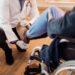Unrecognizable senior man in wheelchair getting his leg examined by a doctor at nursing home.