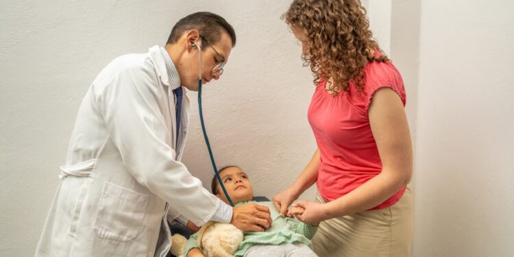 doctor examining child stomach with stethoscope. Pediatrician checking on girl belly at hospital or doctor's office. Hispanic professional working on kids healthcare