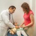 doctor examining child stomach with stethoscope. Pediatrician checking on girl belly at hospital or doctor's office. Hispanic professional working on kids healthcare