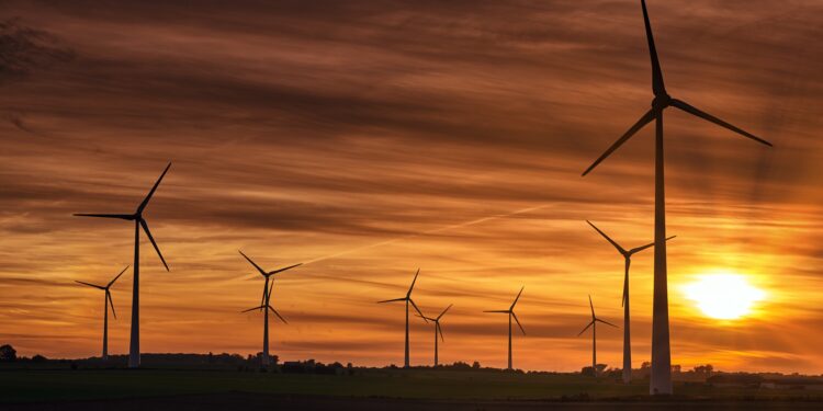A silhouette of windmills on a field during sunset