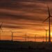 A silhouette of windmills on a field during sunset