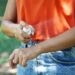 Girl spraying insect repellent on her arm outdoor in nature using spray bottle. Mosquito repellent. Bug spray anti insects.