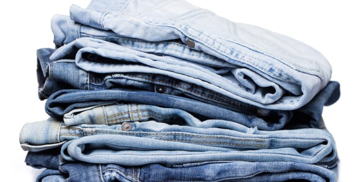 A pile of various pairs of jeans over a white background