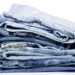 A pile of various pairs of jeans over a white background