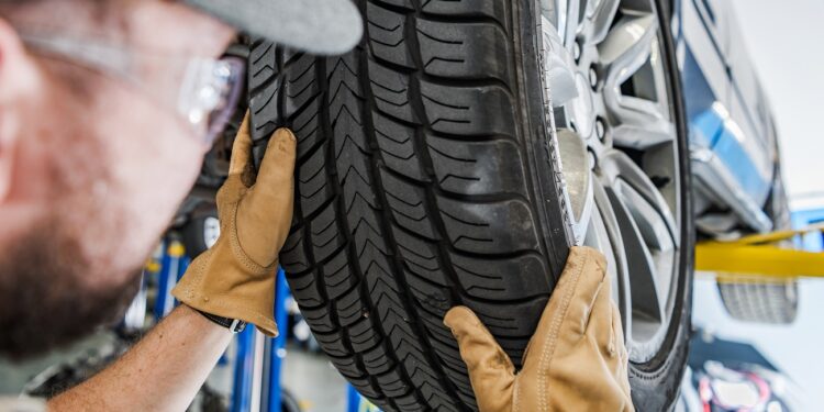 Seasonal Car Tires Change. Replacing Summer Tread to Winter Tread. Automotive Theme. Caucasian Car Service Worker Performing Scheduled Replacement.