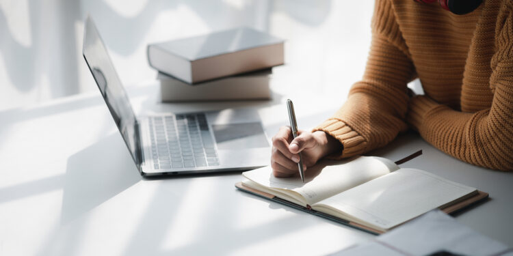 Asian teenage woman sitting in white office with laptop, she is a student studying online with laptop at home, university student studying online, online web education concept.