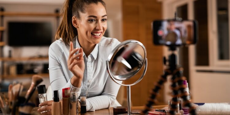 Smiling female influencer talking about beauty products while vlogging from home.