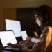 Business people using computers in dark office. Professional male and female business colleagues using laptops with illuminated screens late at night. Working late concept