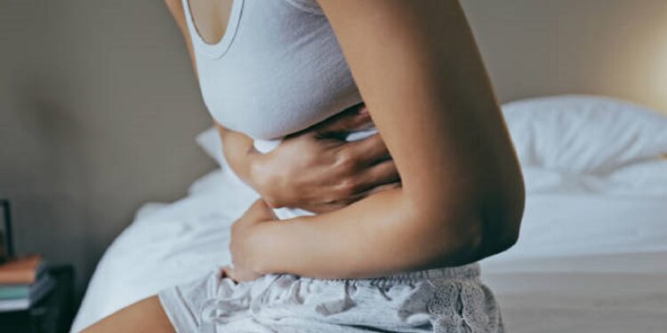 Menstruation, sick and stomach ache with black woman in bedroom for indigestion, cramps and illness. Frustrated, gas and stress with girl on bed for constipation, bloating and intestine problems