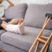 Young Asian man with a broken leg sitting on the sofa. Close up of the crutch.
