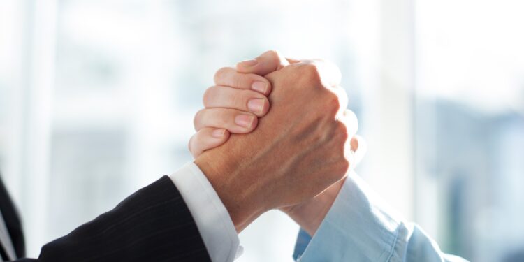 Close-up of two clasped hands of businessmen as sign of strong partnership or team. Unrecognizable men in arm wrestling gesture. Business union concept