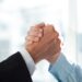 Close-up of two clasped hands of businessmen as sign of strong partnership or team. Unrecognizable men in arm wrestling gesture. Business union concept