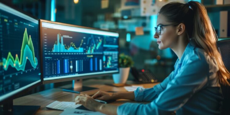 Businesswoman analyzing a line graph on a computer, with notes and reports scattered on her desk.
