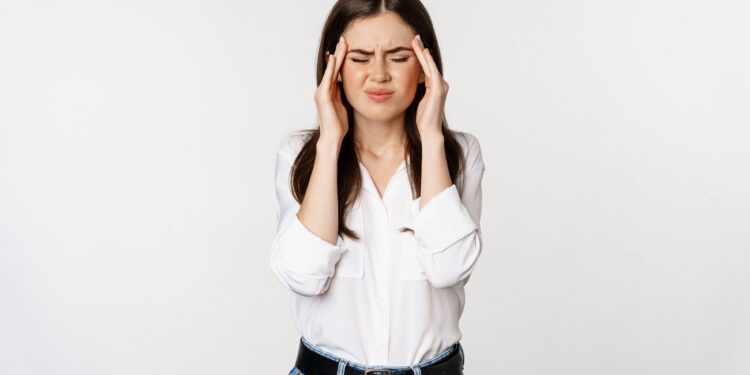 Corporate woman grimacing, touching head, feeling headache, severe migraine, standing over white background.
