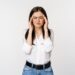 Corporate woman grimacing, touching head, feeling headache, severe migraine, standing over white background.