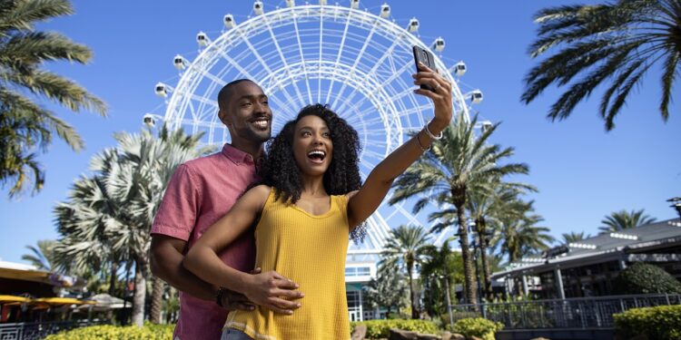 Couple posing for a selfie in front of The Wheel at ICON Park