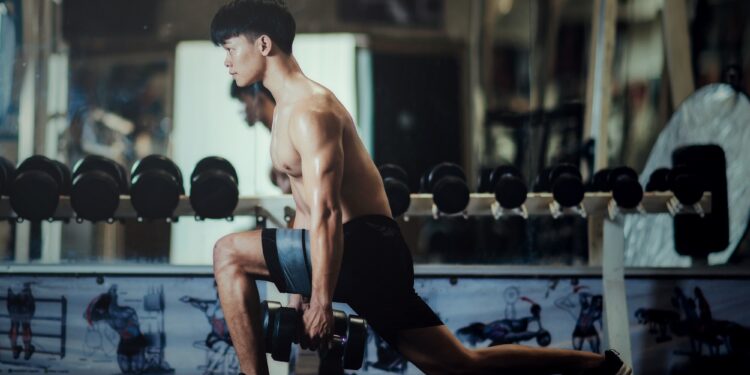Strong bodybuilder with perfect deltoid muscles, Close-up of a Handsome power fitness man in training pumping up muscles with dumbbell.