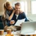 Happy couple analyzing their home budget while paying bill on a computer.