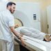 Medical technician starting MRI scanning examination of a female patient at medical clinic.