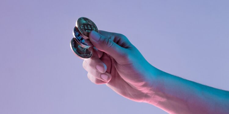 Male hand with golden bitcoin isolated on blue background. Cryptocurrency bitcoin coins. Litecoin, Bitcoin, Ethereum