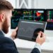 Back view of bearded young businessman sitting and woking with tablet in office