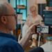 Retired man talking to daughter and niece in hospital on video call, sitting next to crutches. Person using smartphone to chat on online videoconference with relatives at health clinic.