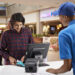 Young man paying for movie tickets at checkout counter in cinema hall