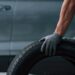 Beautiful shadows. Mechanic holding a tire at the repair garage. Replacement of winter and summer tires.