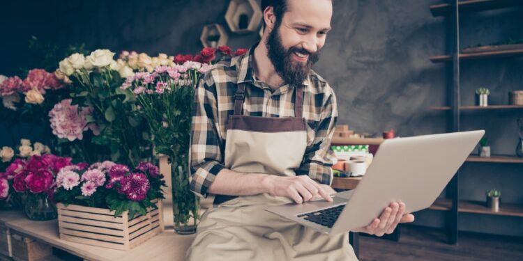 Portrait of his he nice attractive content cheerful cheery positive guy enjoying, life lifestyle browsing surfing web wearing uniform at modern industrial loft concrete style