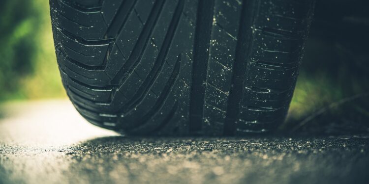 Modern Car Tire on the Road Closeup Photo. Summer Season Pneumatic Tire on a Paved Road.