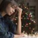 Mixed Race woman with headache near Christmas tree