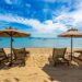 Beautiful tropical beach sea and ocean with coconut palm tree and umbrella and chair on blue sky and white cloud for holiday vacation travel