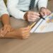Close-up of multiethnic managers discussing international sales while analyzing data. Unrecognizable analysts viewing map while working with statistics. Forecasting concept