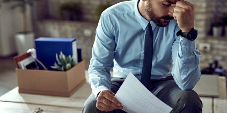 Young frustrated businessman holding his head in pain after being fired at work.