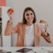 Lady in stylish light outfit shows off her lunch consisting of apple and burger in workplace