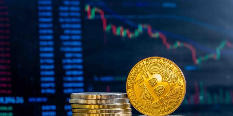 Close-up of golden Bitcoins on a dark reflective surface and the histogram of decreasing crypto in the background