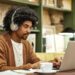 Creative young businessman using laptop in office. Male professional is working at desk. He is wearing smart casual.