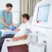 Mid adult female nurse injecting patient for renal dialysis treatment in hospital room