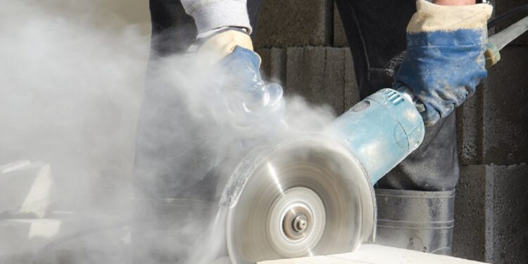 Worker cutting stone with grinder.