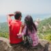 young happy hipster couple in love traveling around world, sightseeing, tropical romantic vacation in thailand, sitting on a rock, pointing finger, active tourism, summer