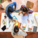 three young architects are having a meeting at a table office studiyng a plan and discussing on a colour chart