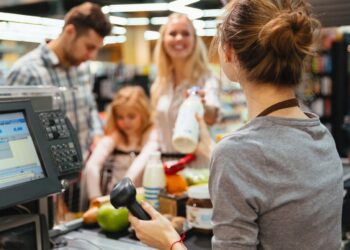 Cheerful family standing at the cash counter buying groceries at the supermarket
