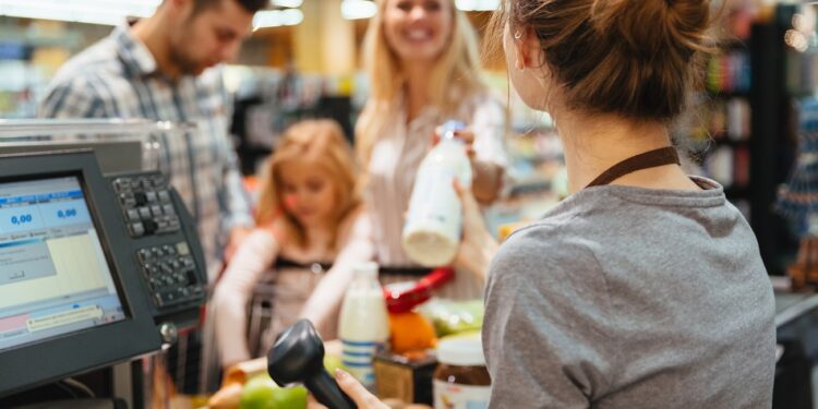 Cheerful family standing at the cash counter buying groceries at the supermarket