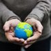 Hands holding a clay globe planet Earth