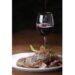 A vertical closeup shot of a freshly grilled T-bone steak and a glass of wine  in the background