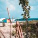 A beautiful shot of a beach with a colorful parasol and a beach chair with amazing waves on a sunny day