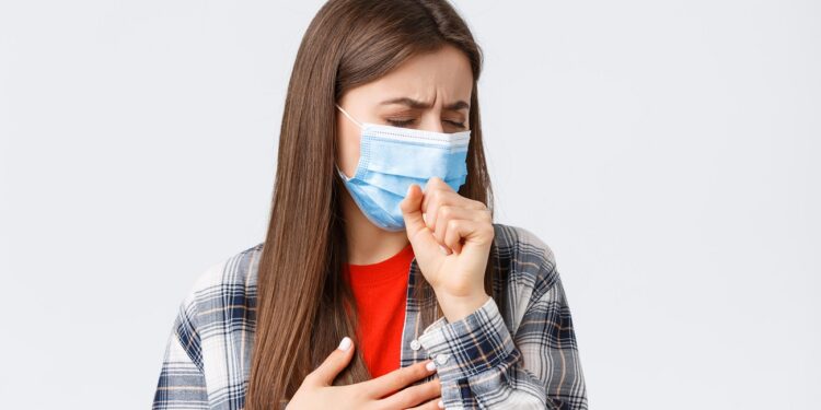Coronavirus outbreak, leisure on quarantine, social distancing and emotions concept. Close-up of sick young woman in medical mask staying at home during covid-19, cough with closed eyes.