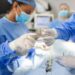 Low Angle Shot in the Operating Room, Assistant Hands out Instruments to Surgeons During Operation. Surgeons Perform Operation. Professional Medical Doctors Performing Surgery.