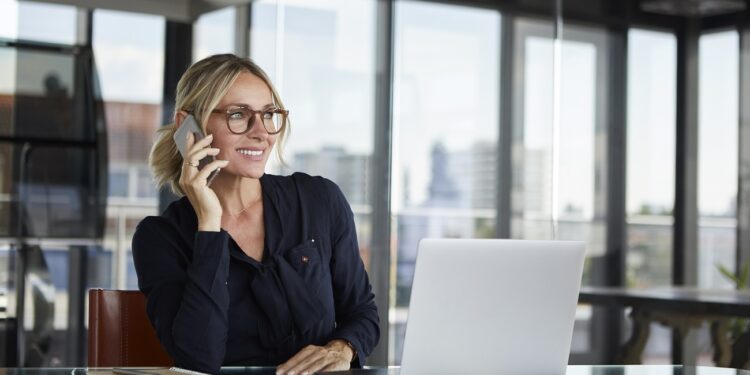 Businesswoman sitting in office, talking on the phone